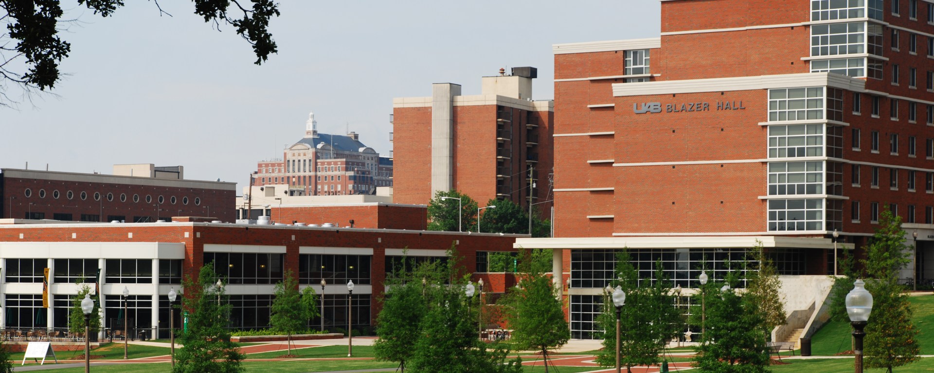 A large red-brick building on the UAB campus, with a small green area in front of it.