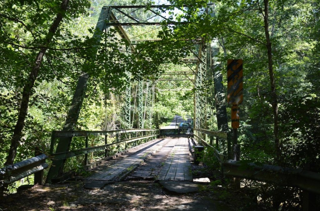 An unused and decaying trestle bridge, surrounded by trees.