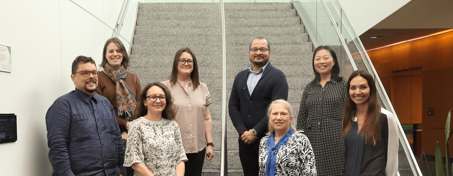 Eight people stand in two rows on a staircase.