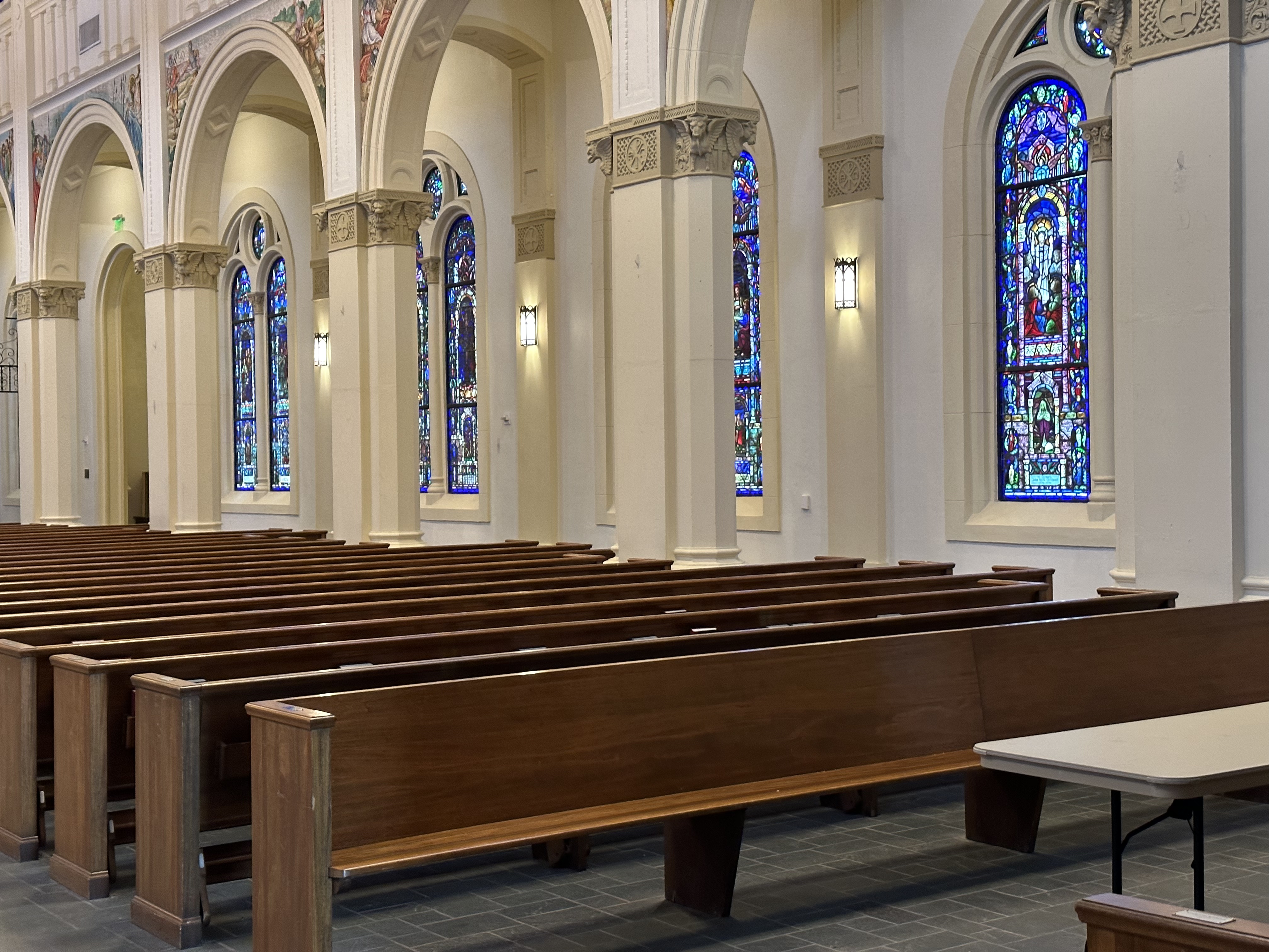 A row of wooden pews with stained glass and columns visible in the background.