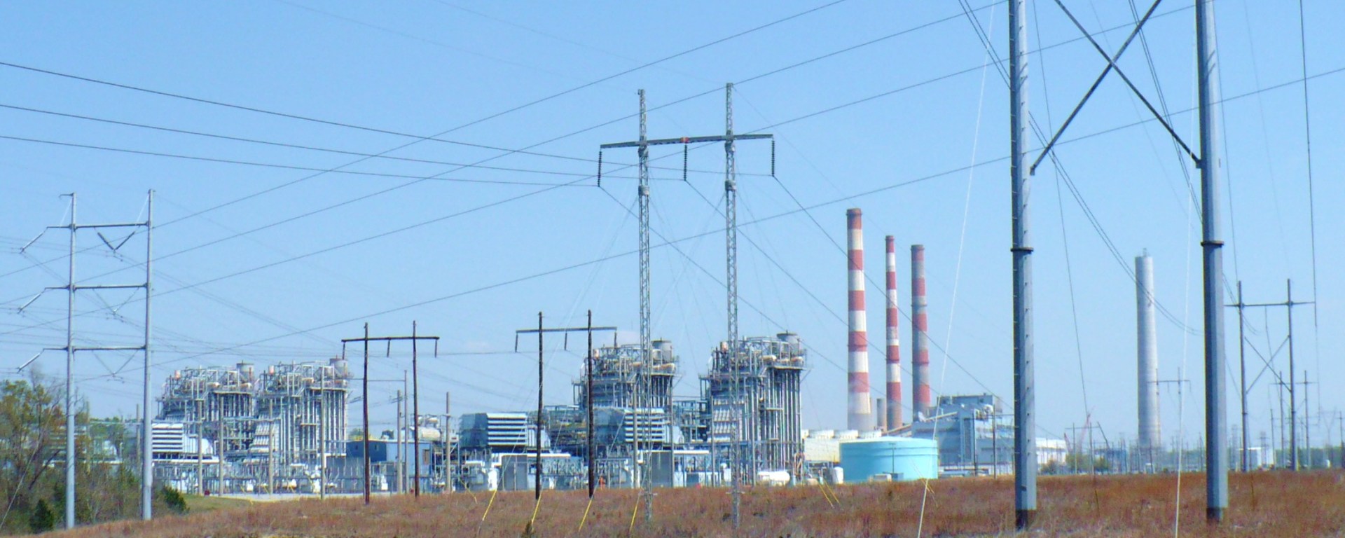 Plant Barry's buildings and smokestacks are visible in the distance. In front of them is a field with large power lines across it.